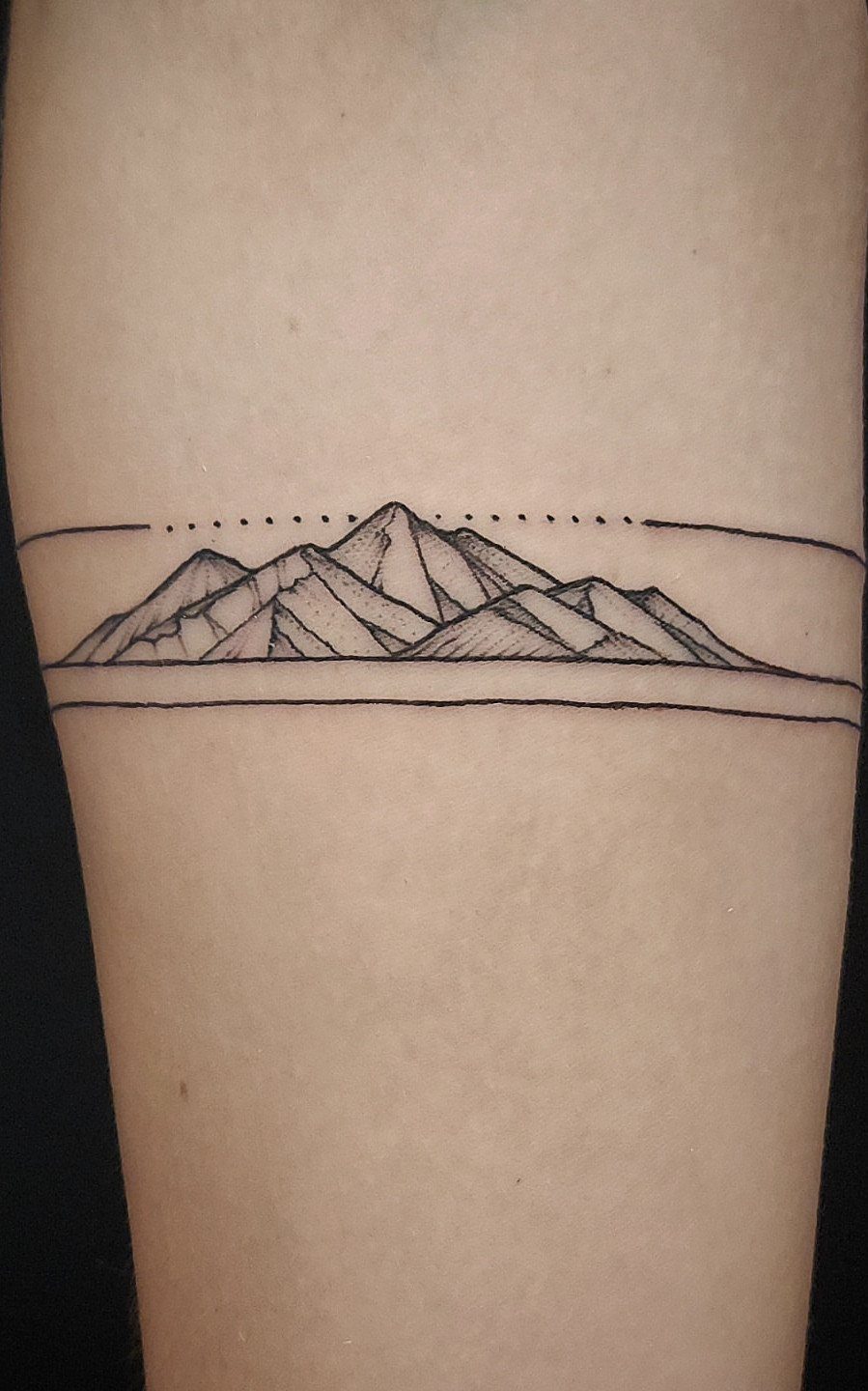 Geometric mountain range tattoo with sharp peaks and horizontal lines on skin.