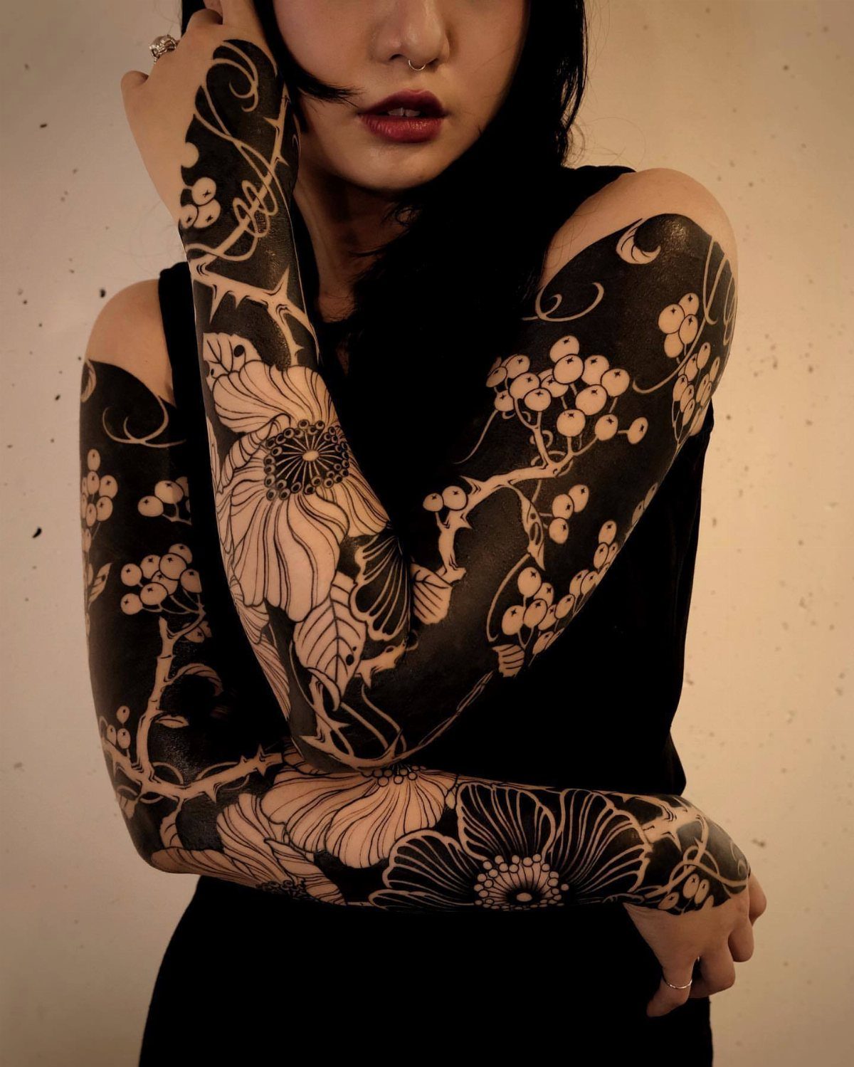 Floral negative space tattoos on a person's arms with black ink and skin contrast.