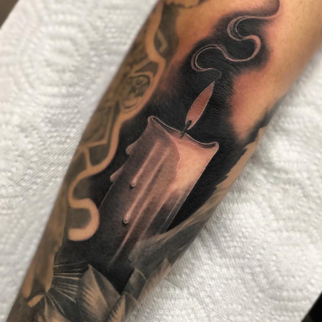 Negative space candle tattoo on an arm with a flickering flame and smoke.