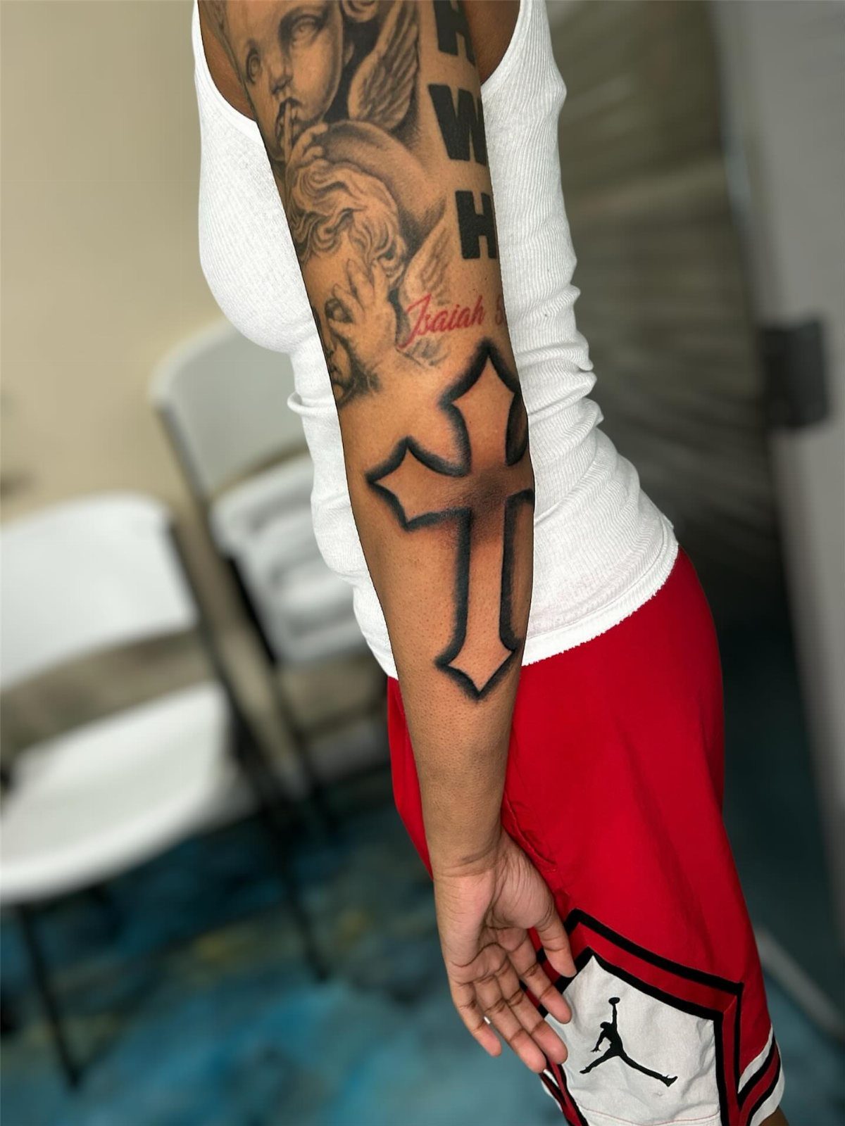 Negative space cross tattoo on a person's forearm with other black ink tattoos.