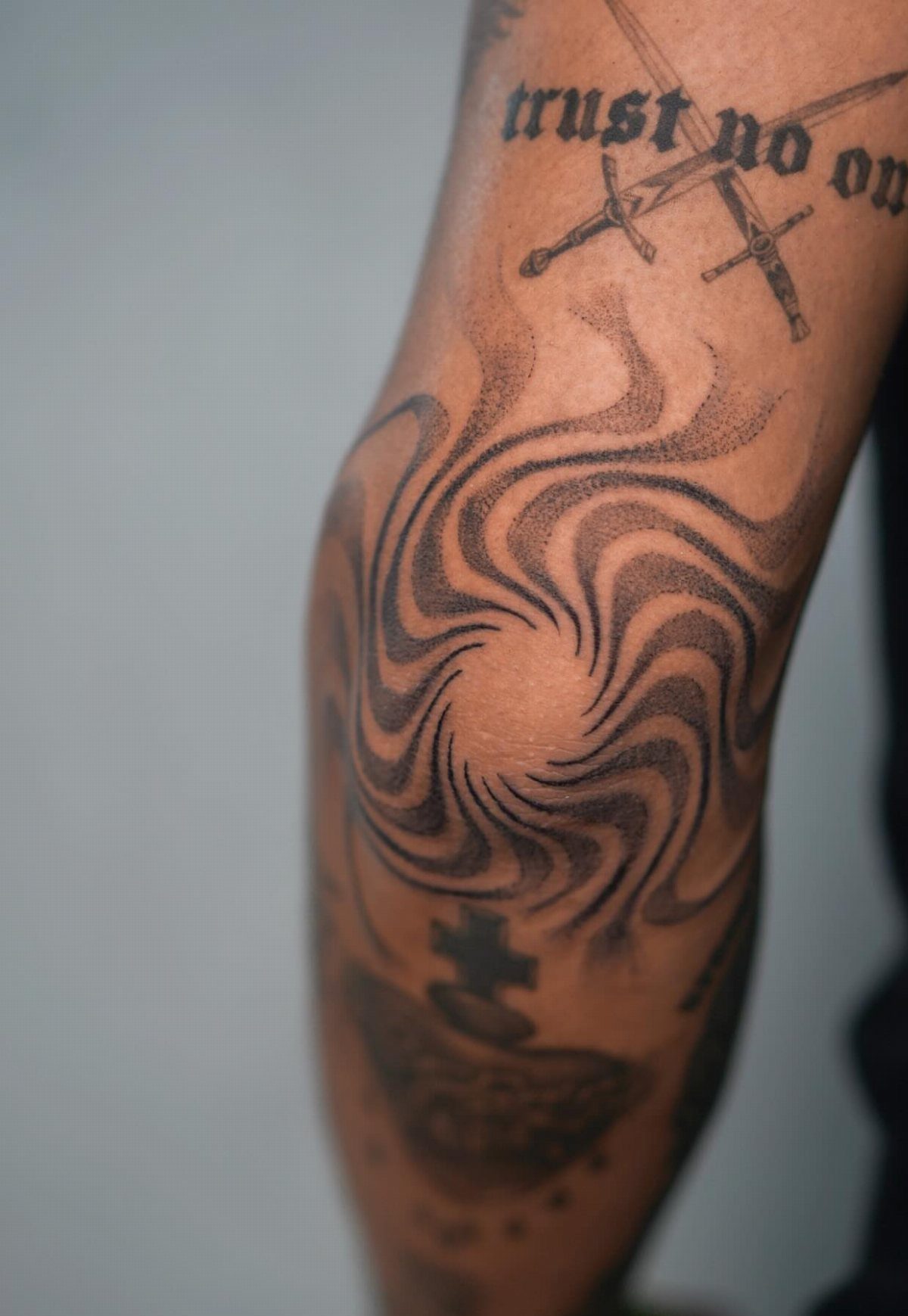 Swirling negative space tattoo on a person's elbow with black ink spiral design.