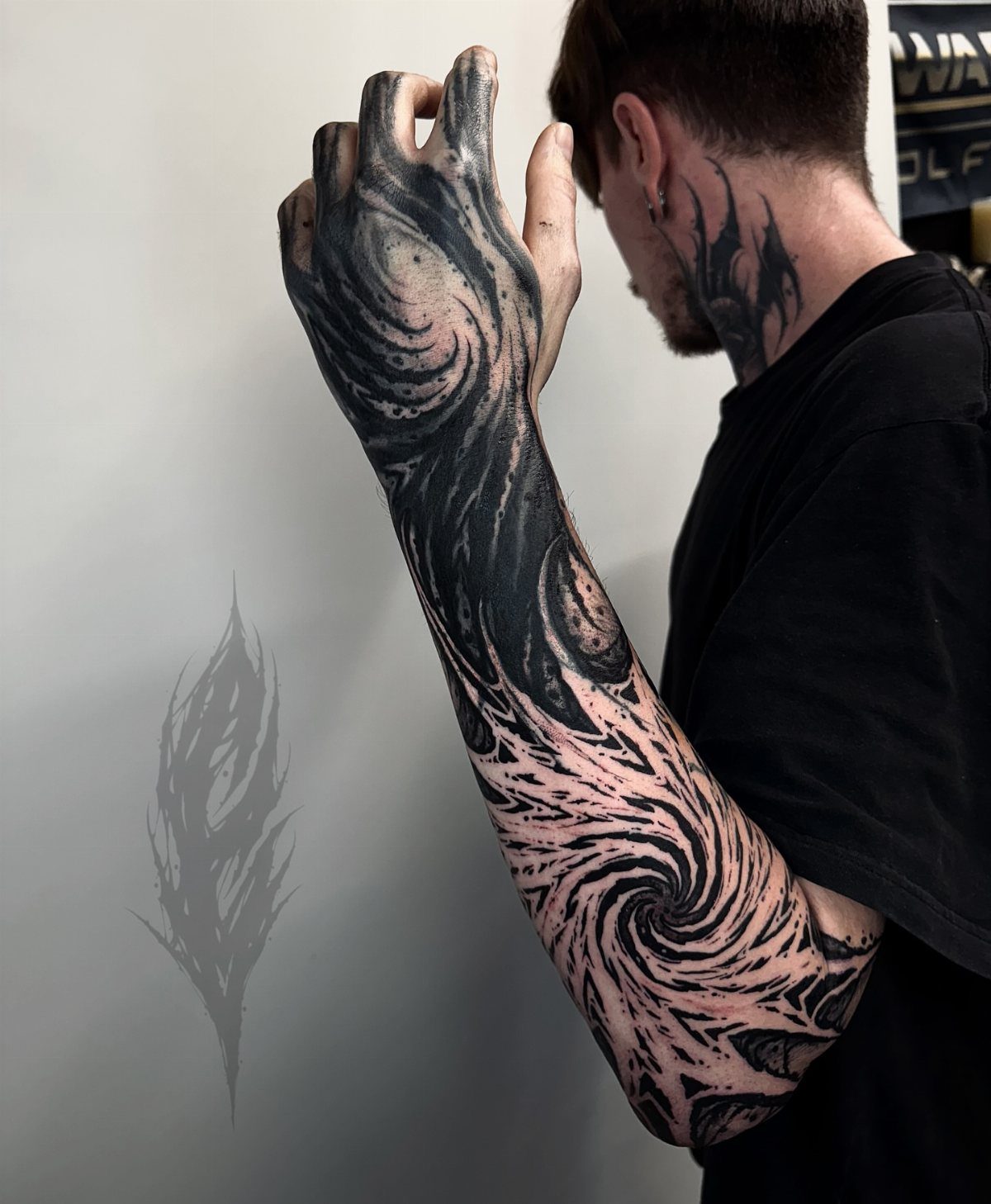 Arm and hand with a black ink swirling negative space tattoo design.