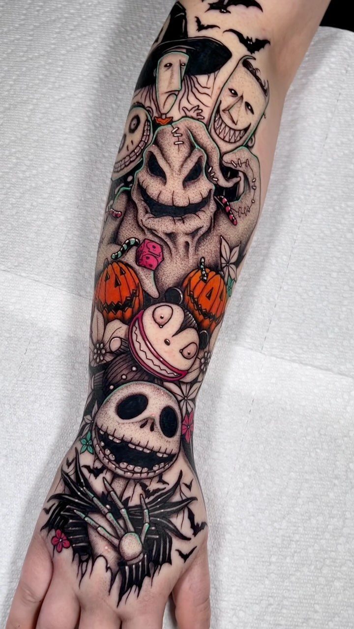 Forearm sleeve tattoo featuring Jack Skellington, Oogie Boogie, and pumpkins in colorful detail.