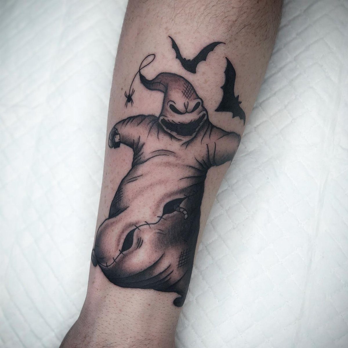 Oogie Boogie tattoo in black and grey ink on a person's forearm.