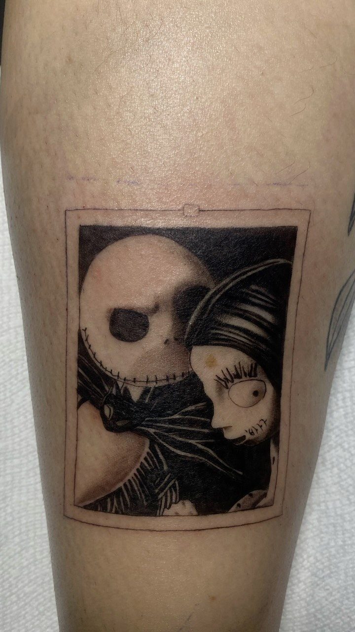 Black and grey tattoo of Jack Skellington and Sally inside a rectangular frame.
