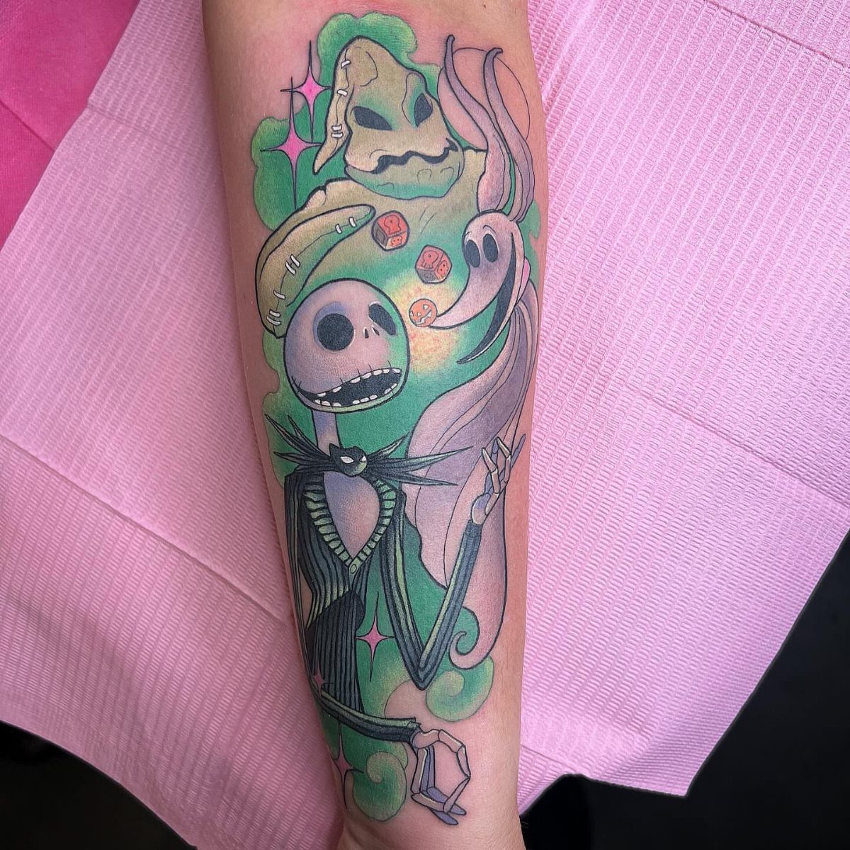 Colorful tattoo of Jack Skellington, Zero, and Oogie Boogie on a person's arm.
