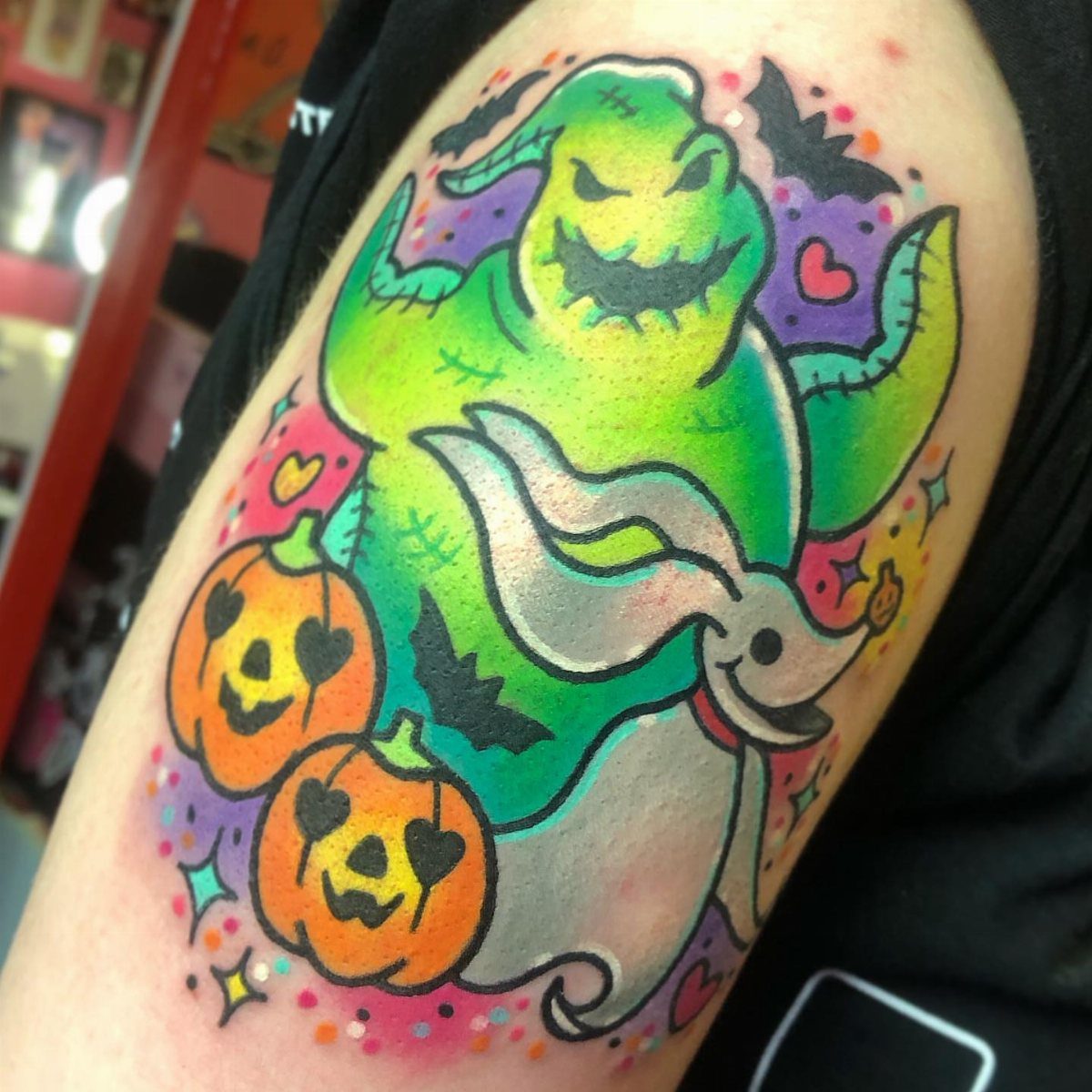 Colorful tattoo of Oogie Boogie and Zero on a person's arm.