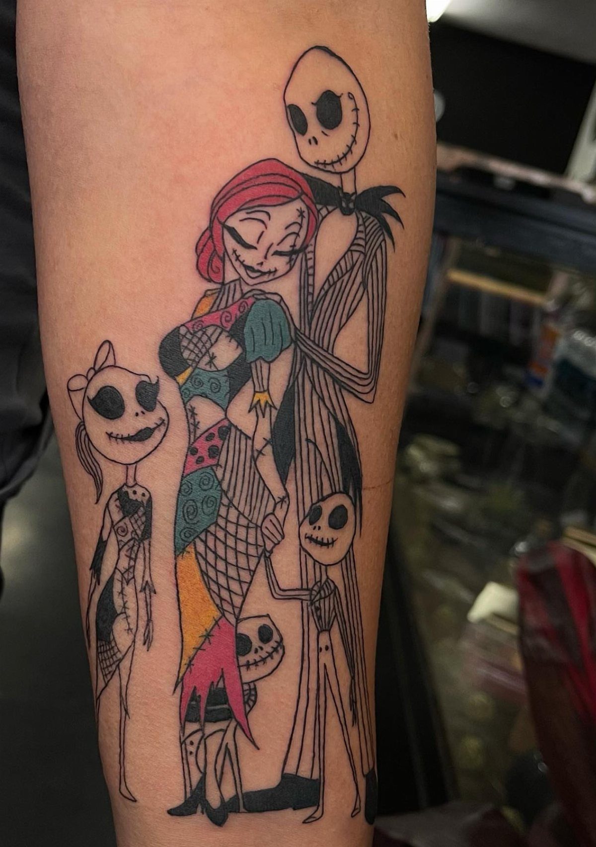 Family portrait tattoo of Jack, Sally, and their children on a person's arm.