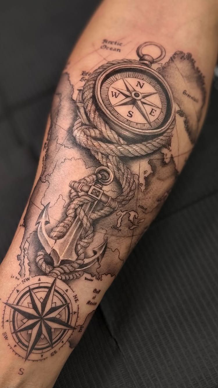 Nautical tattoo on arm featuring a compass, north star, anchor, and vintage map.