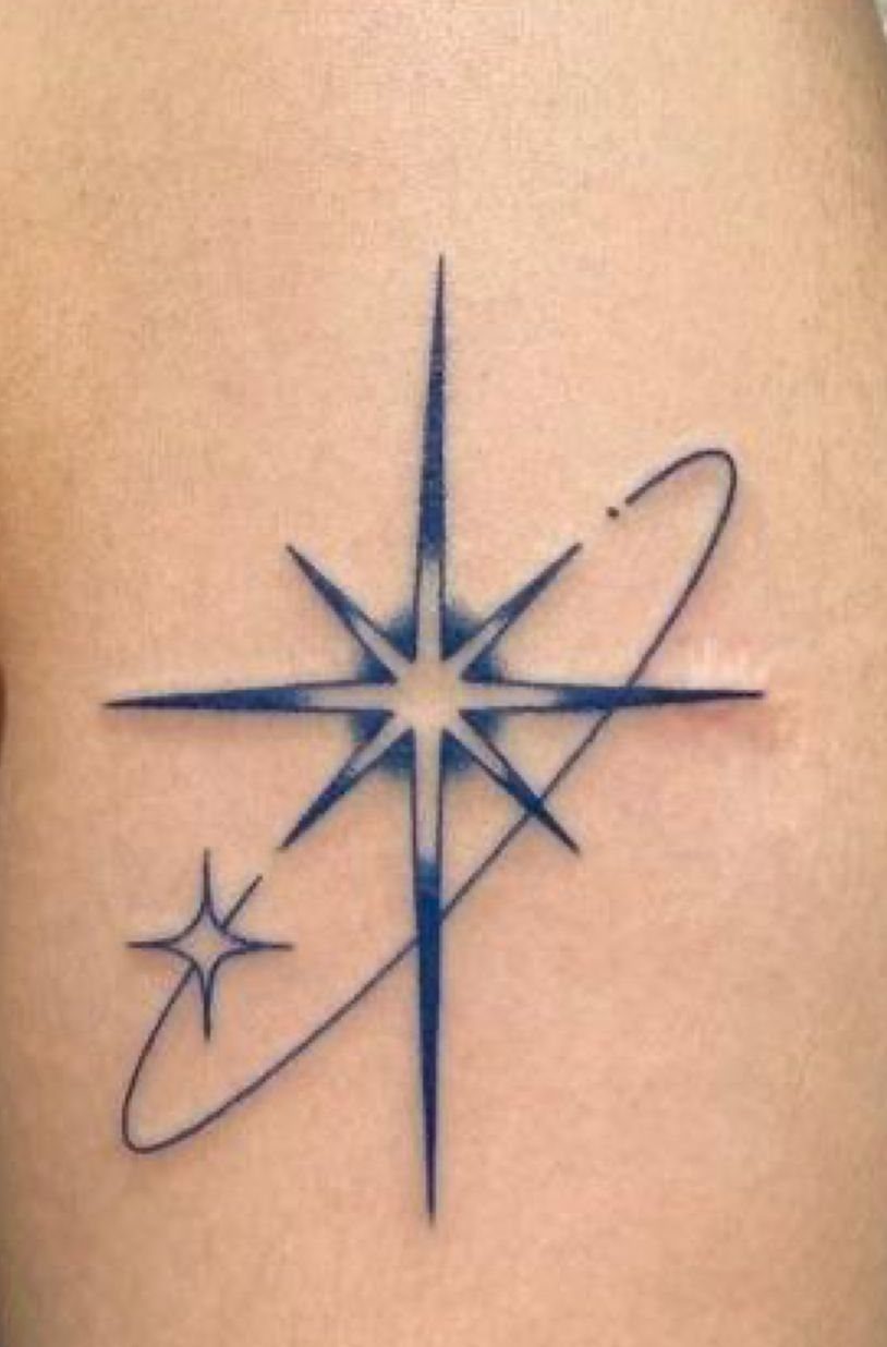 North star tattoo with a smaller star and orbital ring in blue ink.