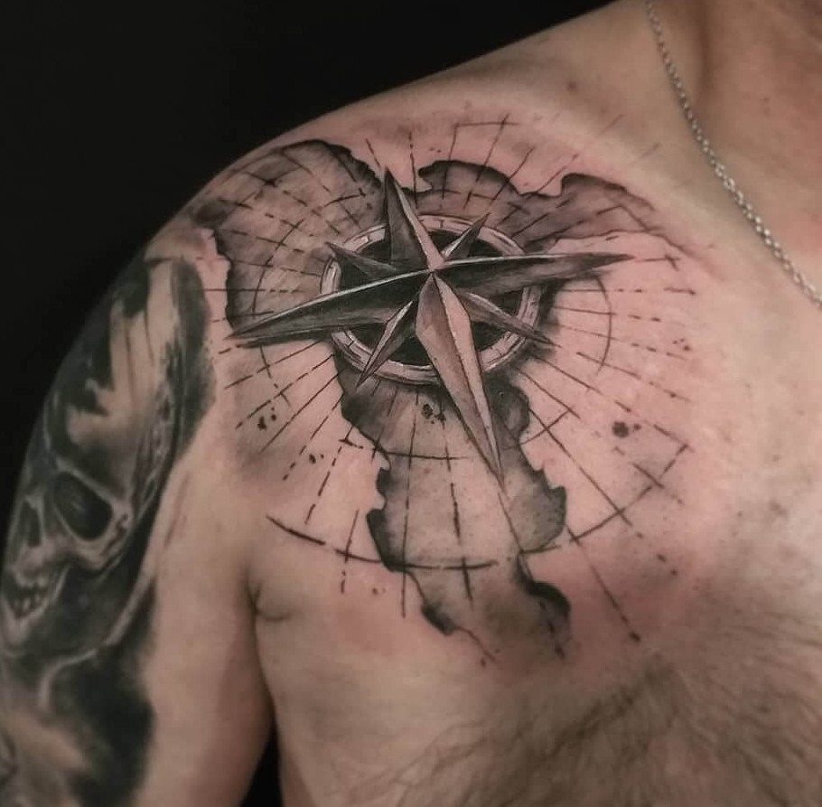 Realistic north star compass tattoo on a man's upper back and shoulder.
