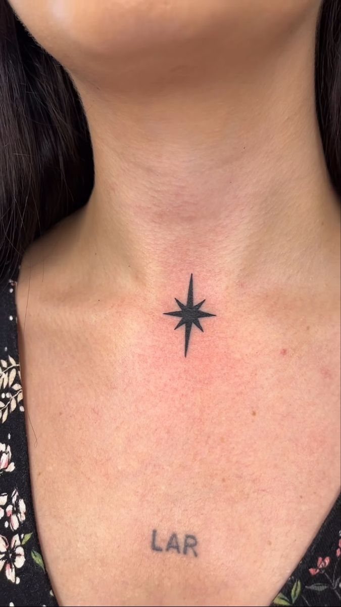 Small black north star tattoo on the center of a person's neck.
