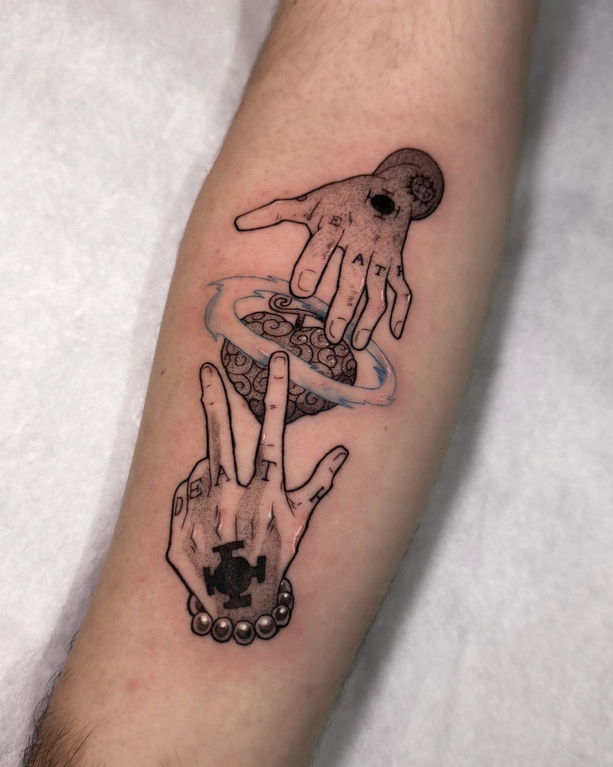 Tattoo on a forearm showing two hands with DEATH written across the knuckles.
