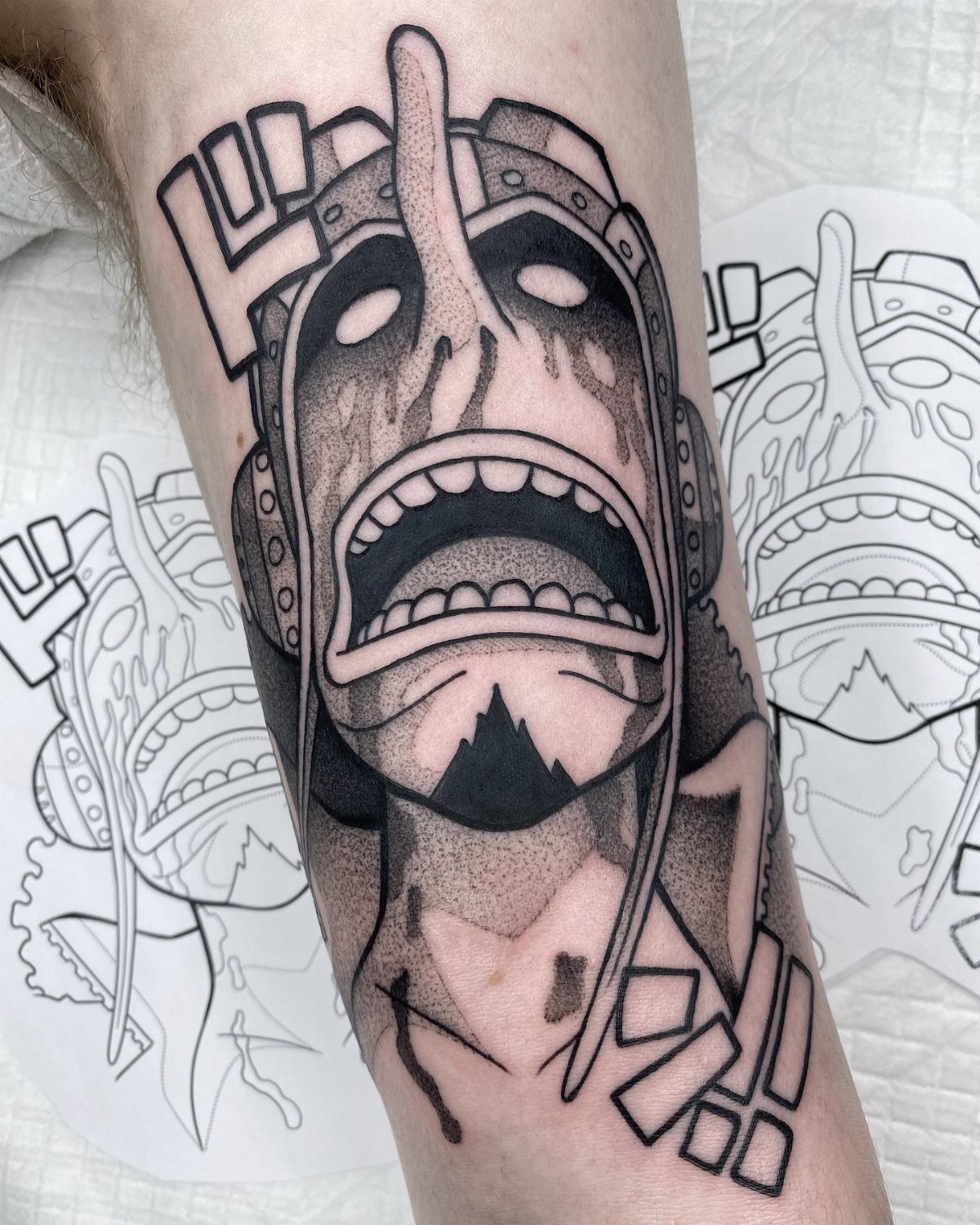 Usopp tattoo on an arm showing his frightened face and long nose.