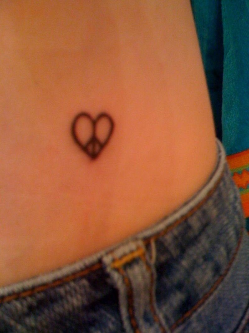 Heart shaped peace sign tattoo on a person's lower torso above denim jeans
