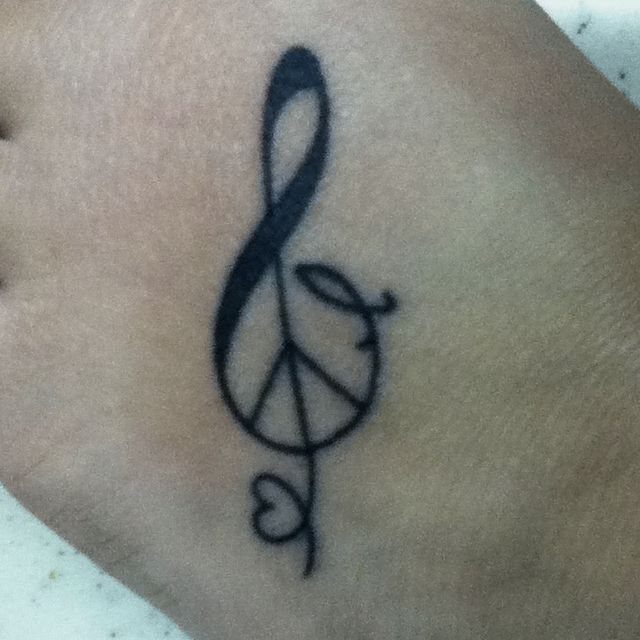 Treble clef and peace symbol tattoo with a small heart on skin.