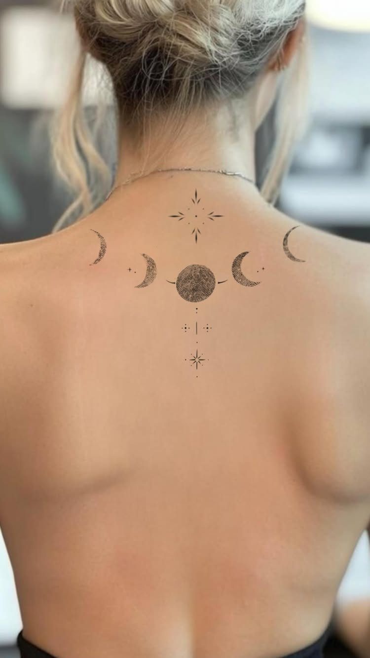 Phases of the moon tattoo on the upper back of a person.