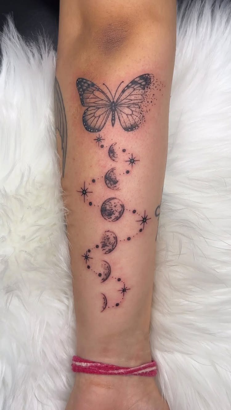 Butterfly and moon phases tattoo with stars on a person's forearm.