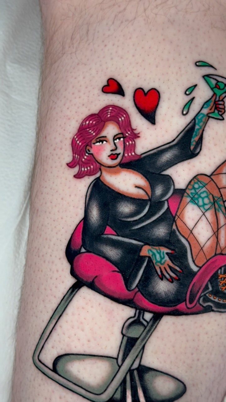 Pin-up woman tattoo with pink hair sitting in a pink chair holding a tool.