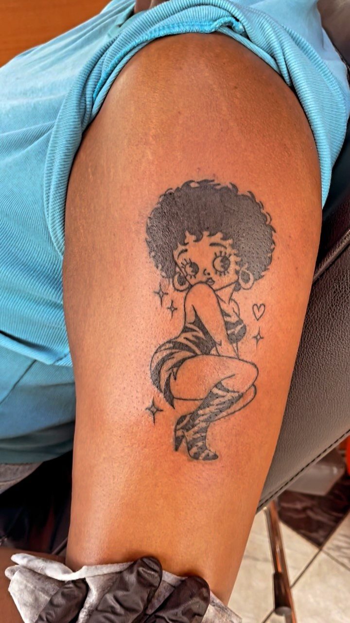Pin up tattoo on a thigh featuring a character with an afro and dress.