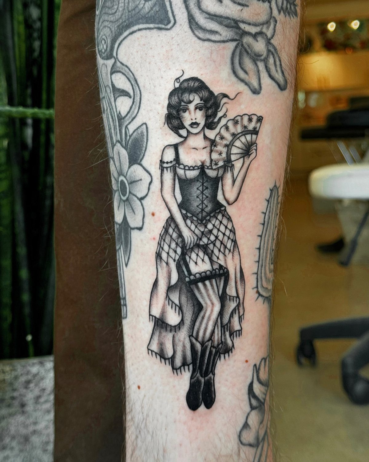 Pin-up woman tattoo with a fan and fishnets on a person's leg