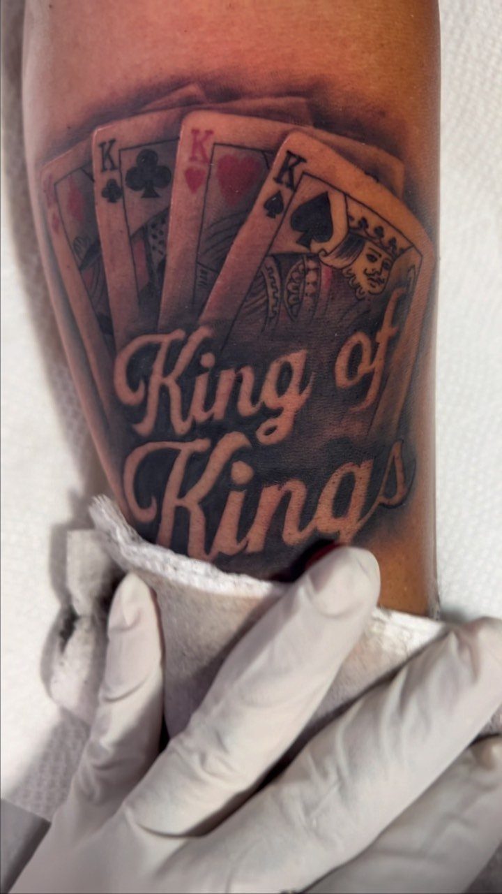 King of Spades playing card tattoo with King of Kings script on forearm