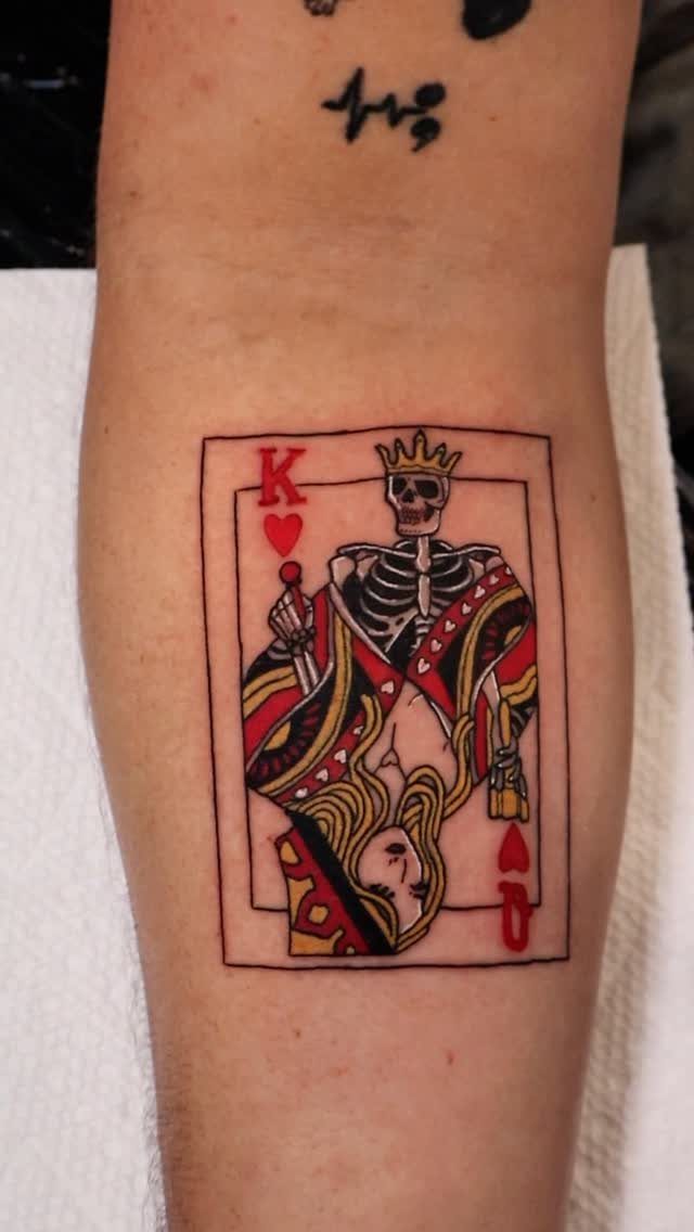 Playing card tattoo on forearm featuring a skeletal king and a woman's face.