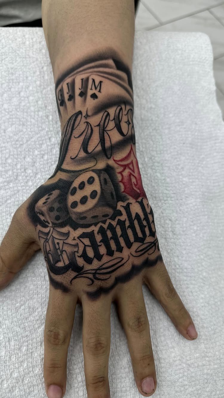 Tattoo on a hand featuring playing cards, dice, and the words Life Gamble.