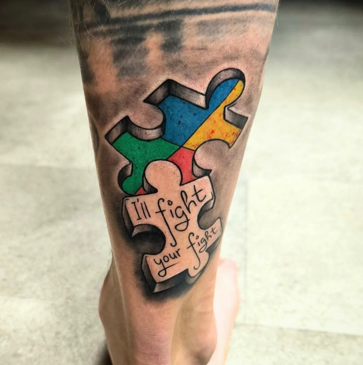 Colorful 3D puzzle piece tattoo on a leg with the words I'll fight your fight.