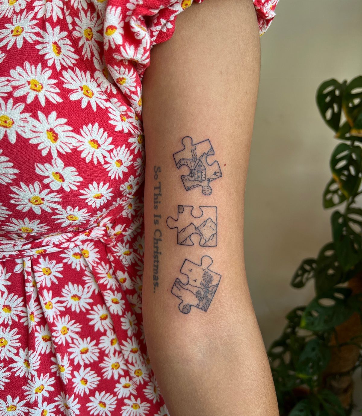Three puzzle piece tattoos with landscape scenes on a person's upper arm.