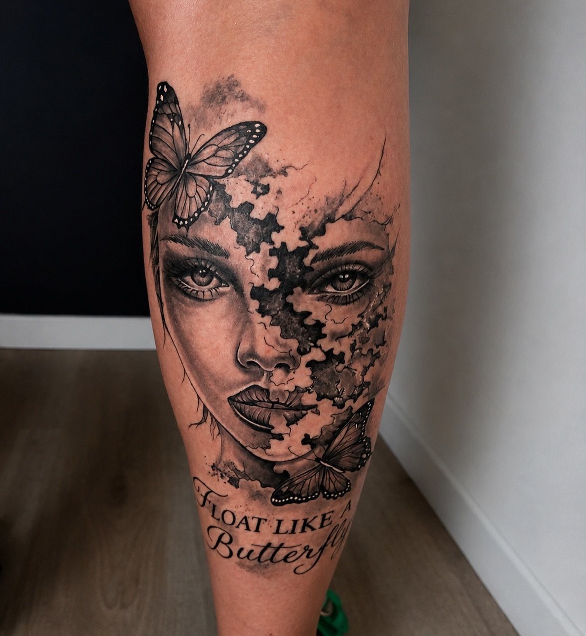 Tattoo of a woman's face merging with puzzle pieces and two butterflies.