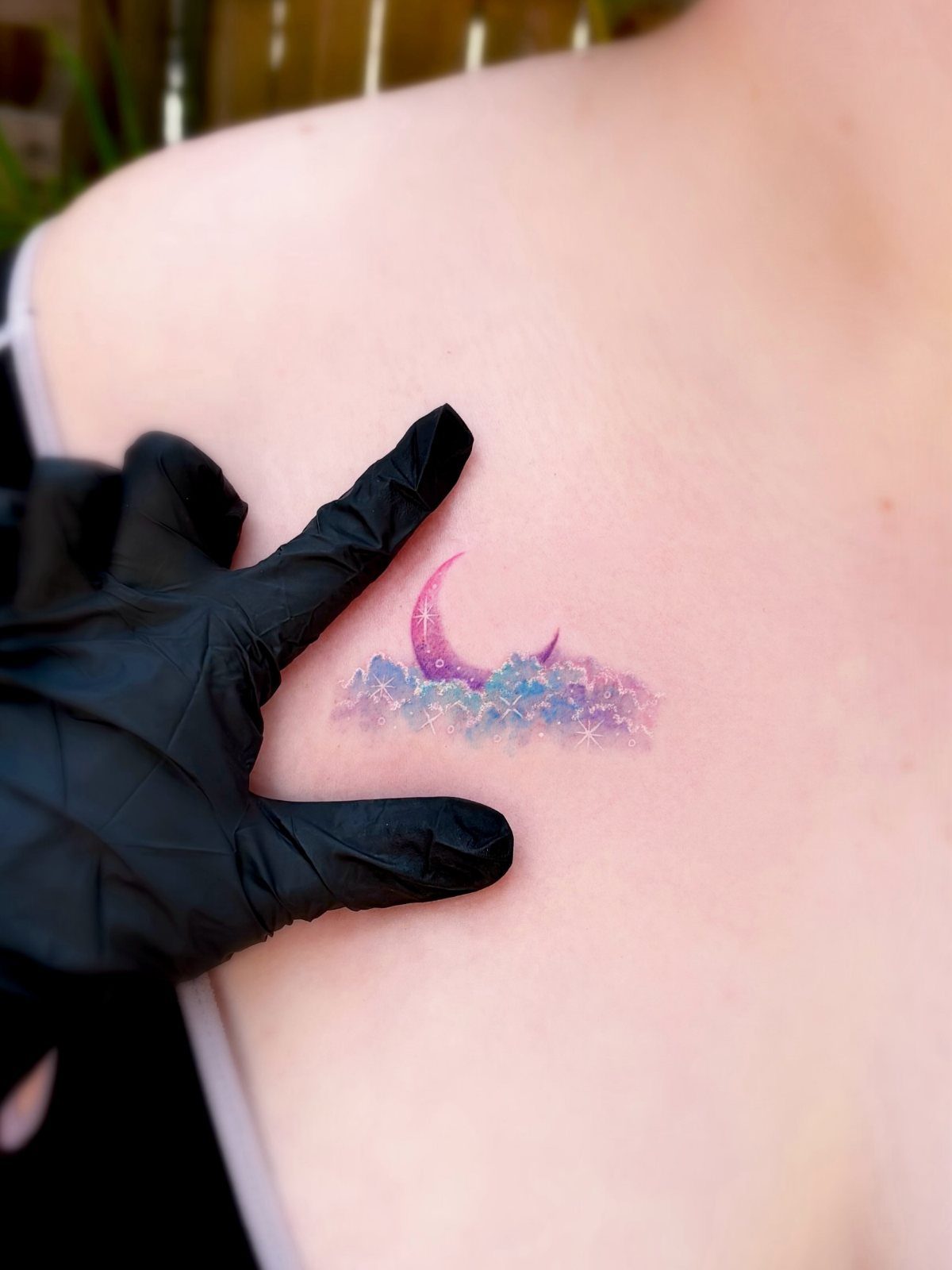 Crescent moon and watercolor cloud tattoo on a person's shoulder