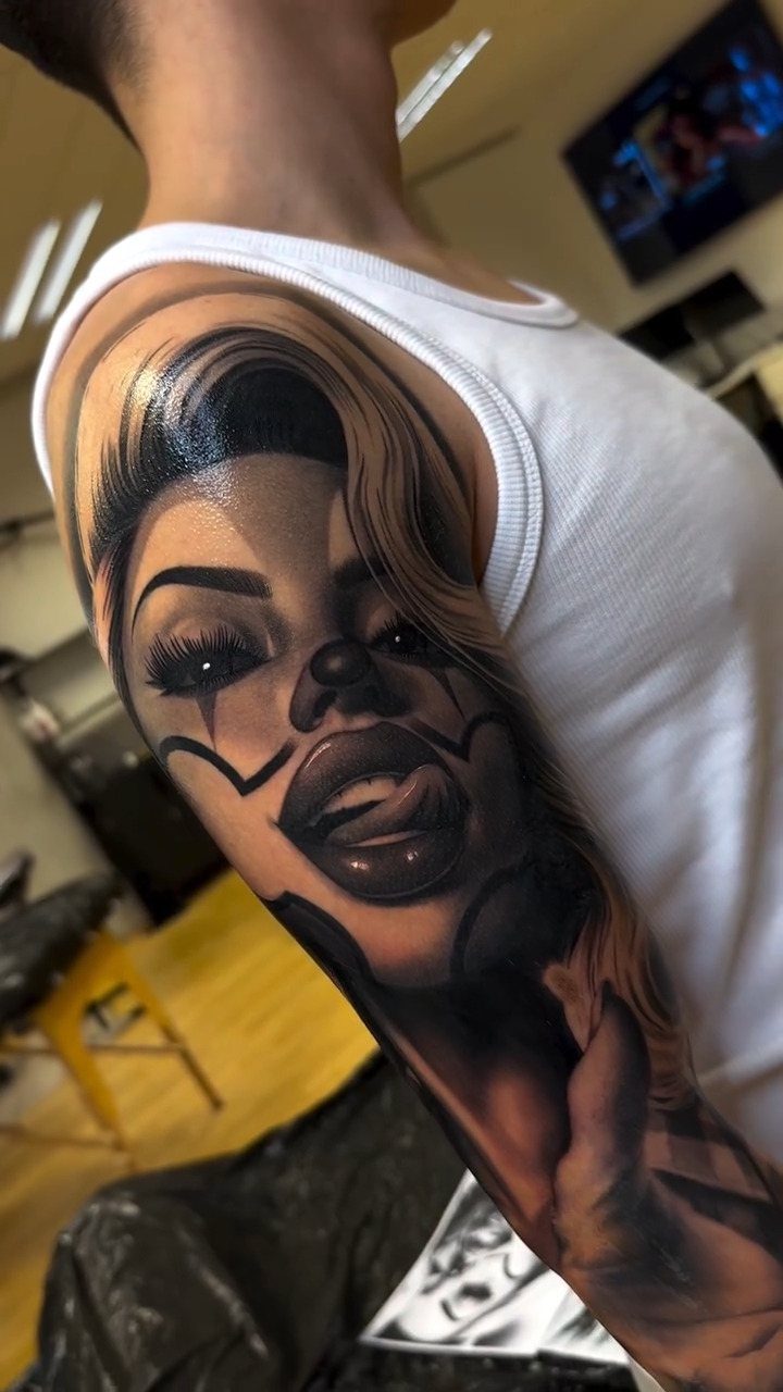 Realistic black and grey tattoo of a woman with clown makeup on an arm