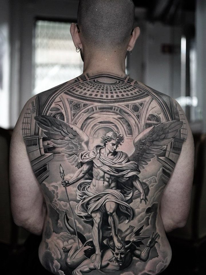 Detailed black and grey tattoo of an angel defeating a demon on a man's back.
