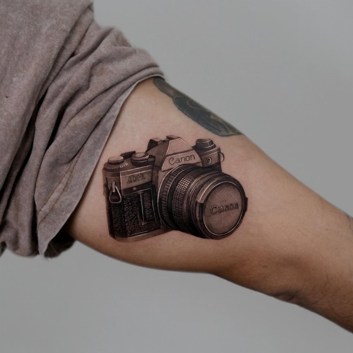 Vintage Canon camera tattoo with detailed shading on a person's forearm.