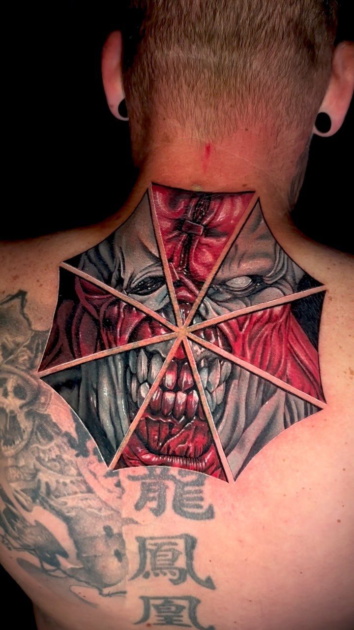Umbrella Corporation logo tattoo on a man's back featuring Nemesis's face inside.