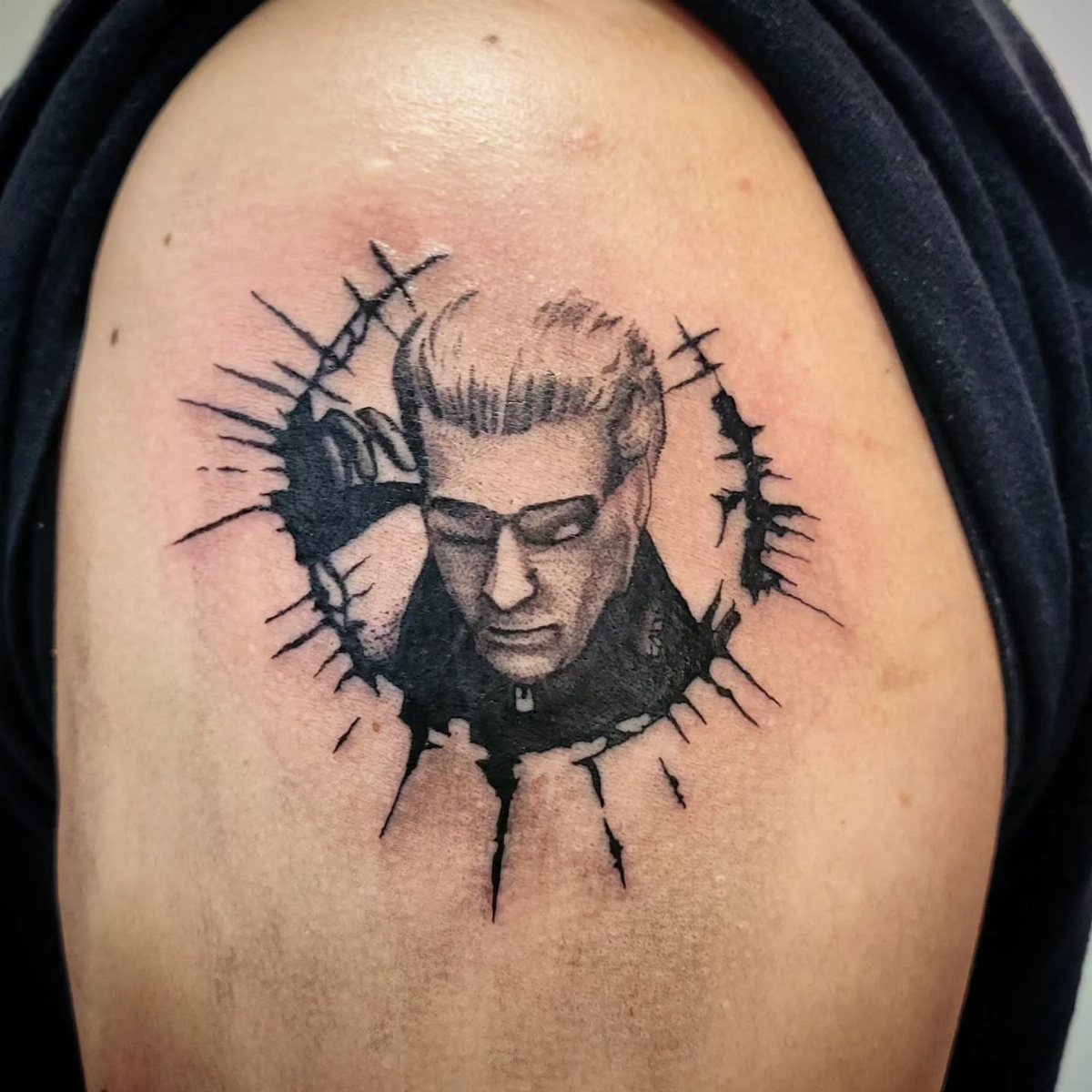 Albert Wesker tattoo on a shoulder with a black ink splatter border.