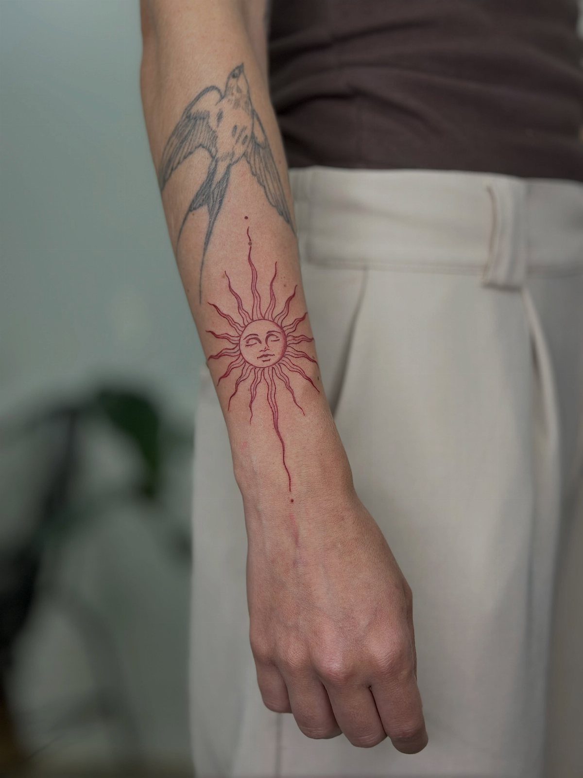 Red sun tattoo with a face on a person's forearm