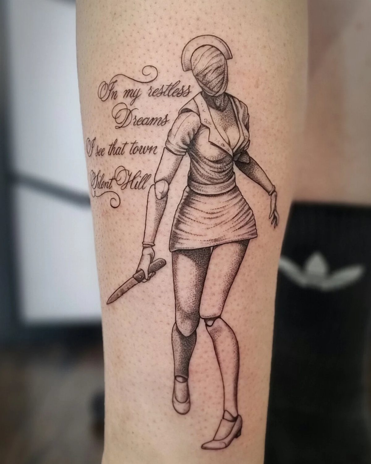 Nurse tattoo from Silent Hill with accompanying cursive text on human skin.