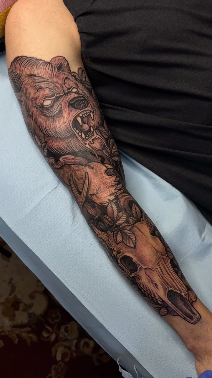 Bear skull and roaring bear head tattoo on a person's forearm.