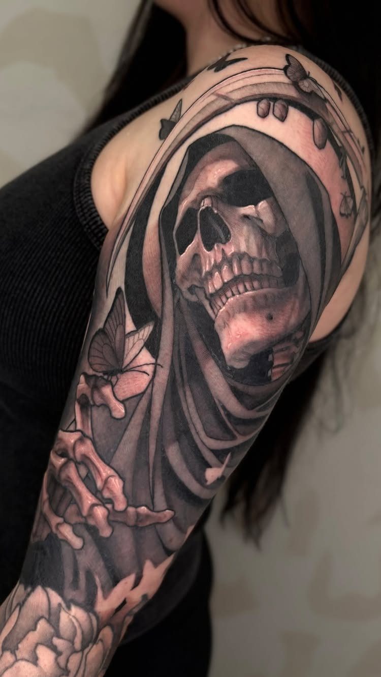 Grim Reaper tattoo on an arm featuring a hooded skull and skeletal hand.