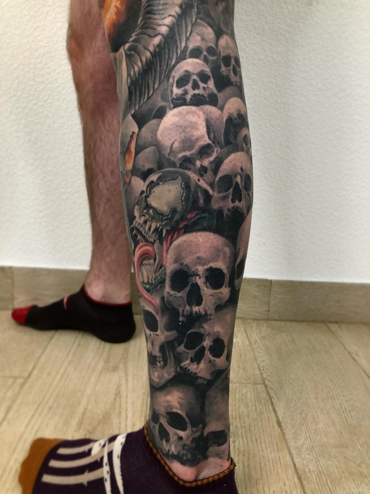 Realistic black and grey skull tattoo covering a person's lower leg and calf.