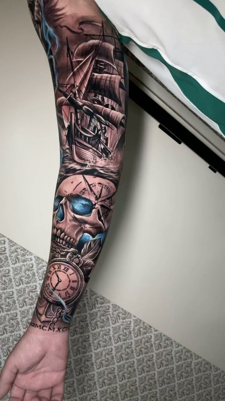 Sleeve tattoo featuring a pirate ship, a skull, and a vintage pocket watch.