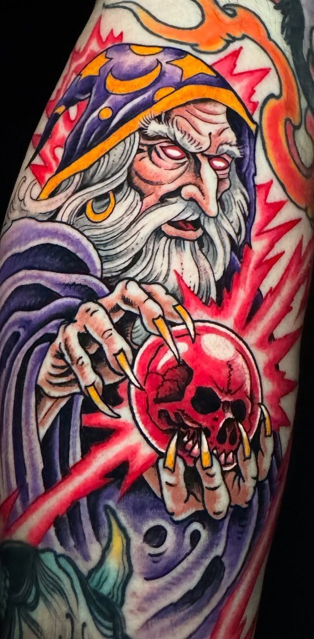 Wizard tattoo with purple robes holding a glowing red skull in his hands.