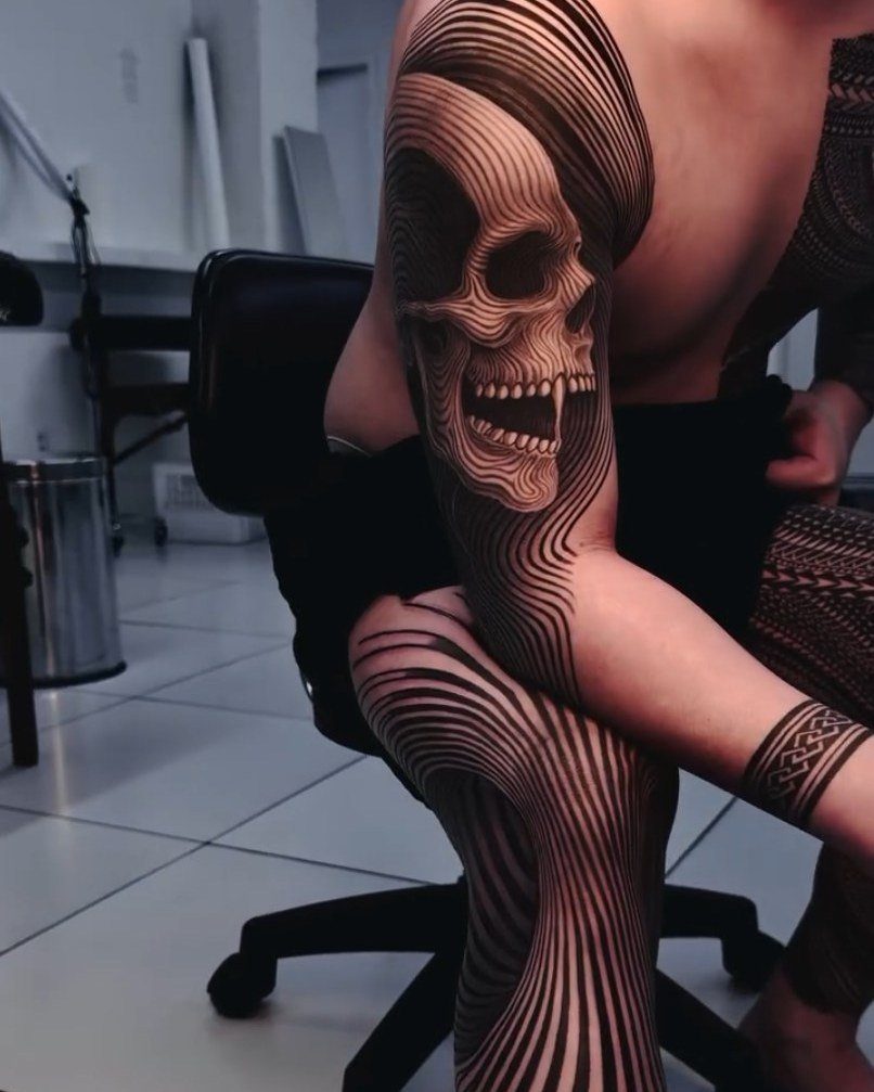 Skull tattoo on an arm integrated into flowing, distorted black and white lines.