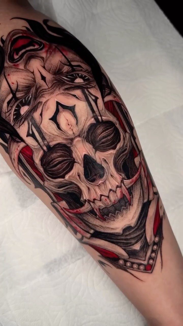Vampire skull tattoo with long fangs and a distorted face on an arm.