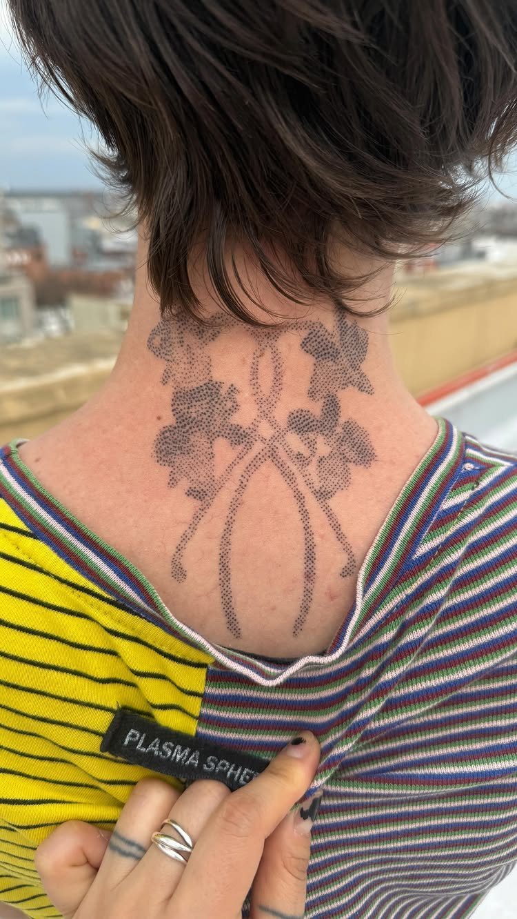 Stippled black ink tattoo on the back of a person's neck and shoulders.