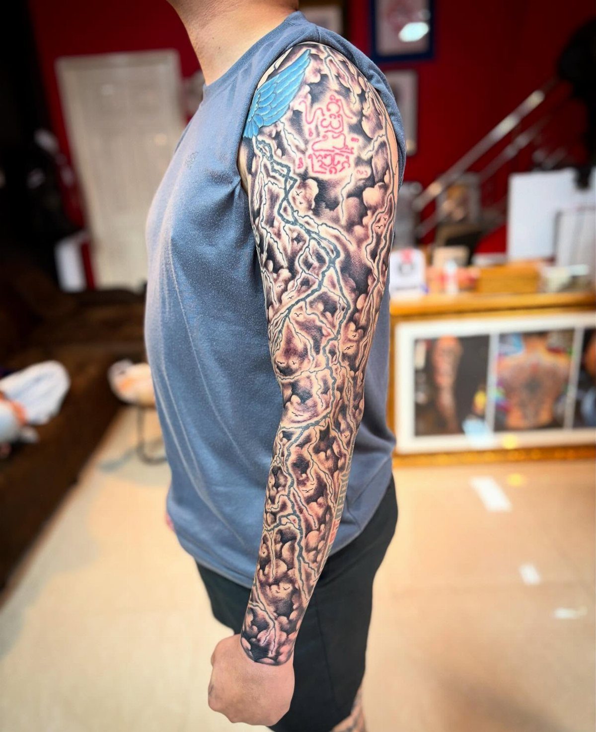 Realistic storm cloud tattoo sleeve with lightning bolts on a man's arm.