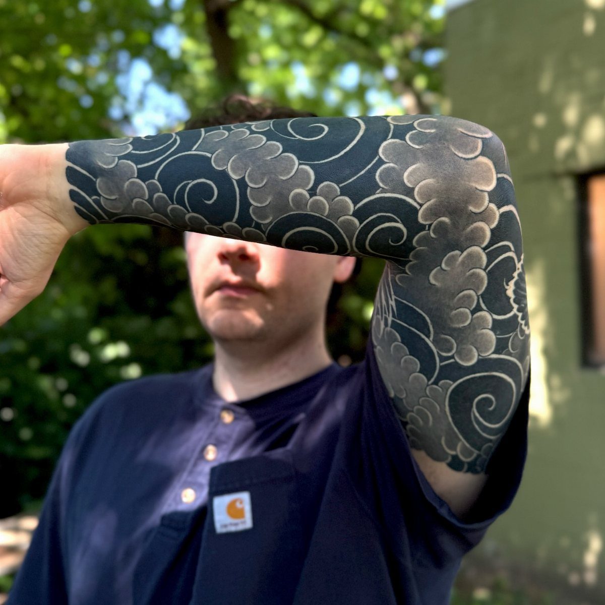 Arm sleeve tattoo featuring dynamic, swirling dark grey and black cloud patterns.