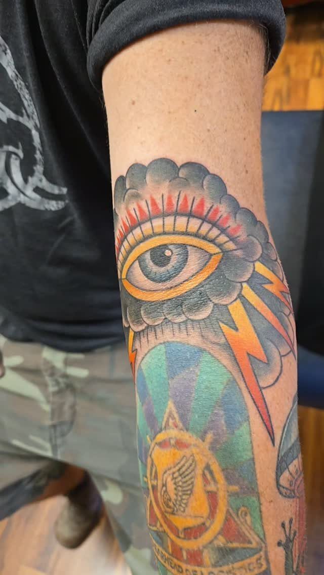 Traditional storm cloud tattoo with an eye and lightning bolts on an arm.
